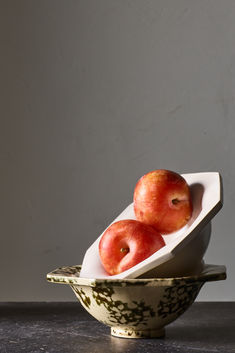 two apples in a bowl on a table