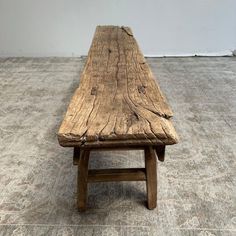 a wooden bench sitting on top of a carpeted floor next to a white wall