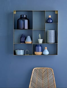 blue vases and other decorative items are arranged in a shelving unit on the wall