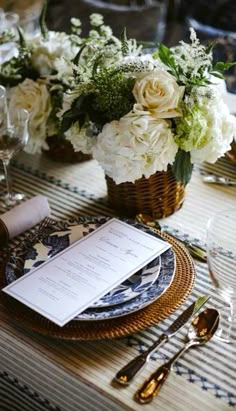 the table is set with white flowers and place settings