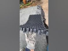 a person standing next to a pile of black plastic cups on top of a cement slab