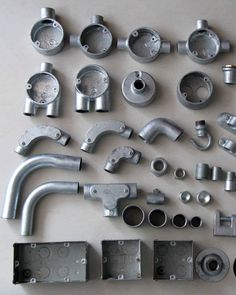 various metal parts are laid out on a table top, including pipes and fittings