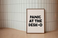 there is a sign that says panic at the desk - o in front of a tiled wall