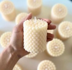 a person holding a candle in front of some small white circles on a plate with one hand