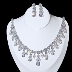 A luxurious two-piece bridal jewelry that will add elegance and sophistication to any wedding gown or formal ensemble! Adorned with intricately faceted cubic zirconia that capture the light from every angle with a perfectly translucent appeal, the pieces are platinum plated for a flawless finish which enhances the intricate detailing and conveys a modern take on old elegance. Necklace: 42cm (approx. 16.5") long with a secure fold-over closure (a 2" extension chain can be added upon request, plea Crystal Wedding Tiaras, Glow Jewelry, Bridal Earrings Chandelier, Crystal Chandelier Earrings, Crystal Statement Necklace, Bridal Necklace Set, Silver Wedding Jewelry, Bridal Jewelry Set, Womens Wedding Dresses