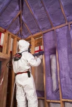 a man in white coveralls spray painting the inside of a house with purple walls