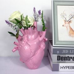 a pink vase with flowers in it next to books