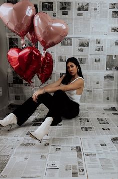 a woman sitting on the floor with two heart shaped balloons