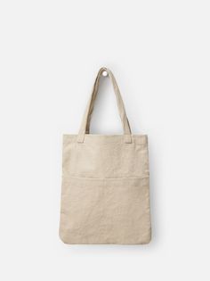 a beige canvas bag hanging on a white wall