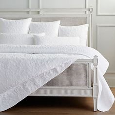 a bed with white sheets and pillows on it