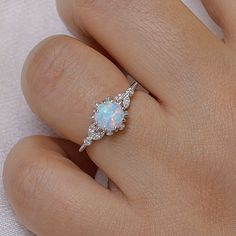 a woman's hand with a white opal and diamond ring on her finger