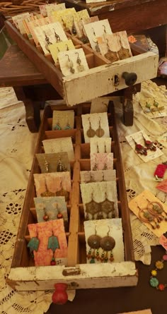 an old wooden box filled with earrings on top of a table covered in doily