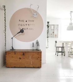 a white room with a wooden chest and sign on the wall that says add little confection each day