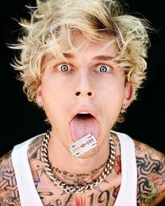 a man with tattoos and piercings sticking his tongue out in front of the camera