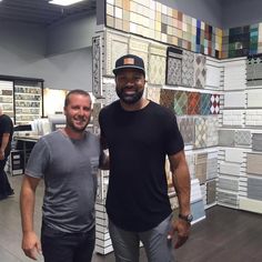 two men standing next to each other in a room with lots of tiles on the walls