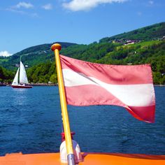 a flag on the back of a boat with sailboats in the water behind it