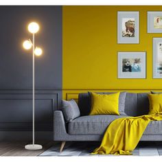 a living room with yellow walls and grey couches in front of pictures on the wall