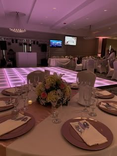 a table set up with place settings and flowers in front of a large screen tv