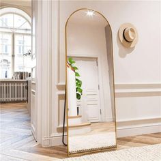 a large mirror sitting in the middle of a room next to a wall with a hat on it