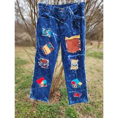 a pair of blue jeans with patches on them hanging from a clothes line in front of a tree