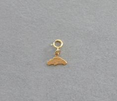 a small gold charm with a car on it's front end and a keychain hanging from the side