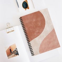 an open spiral notebook sitting on top of a desk next to a pair of scissors