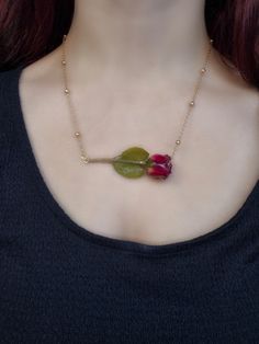 Red roses are often associated with love since the color remembers the passion of the fire. You can gift this red rose to your lover or yourself since it's a delicate and unique addition to every jewelry collection. This Red Rose necklace comes with a stylish beaded chain. The dried flower pendant is genuine and covered in resin. Its size is around 2 cm but may vary since flowers come in different sizes. The rose bud and the stem measure around 4-5 cm in total. The chain is approximately 21 cm long. This necklace is available in two chain options - a 925 sterling silver chain or an 18k gold plated chain - so you can choose the one that best suits your style. Both chains measure around 21 cm, and the 925 sterling silver chain has smaller beads than the 18k gold-plated one. This necklace is Rose With Stem, Flower In Resin, Dried Flower Jewelry, Jewelry Real, Rose Bud, Rose Pendant, Rose Necklace, Rose Rouge, Blooming Rose