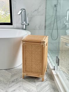 a wicker cabinet in the middle of a bathroom next to a bathtub and shower