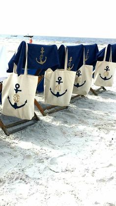 row of beach chairs with blue and white tote bags lined up on the beach