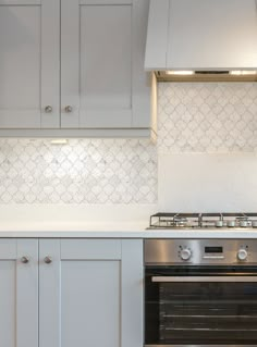 a stove top oven sitting inside of a kitchen next to white cupboards and counter tops