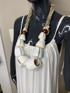 a mannequin wearing a white dress with gold chains and beads on it's neck