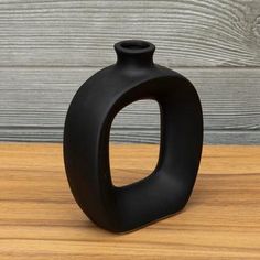 a black vase sitting on top of a wooden table