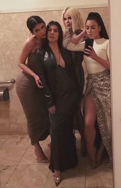 three women standing in front of a mirror taking a selfie