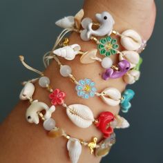 a close up of a person's arm with various bracelets on it, including sea shells and seashells