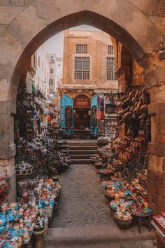 an archway leading to a market with lots of items on display in front of it