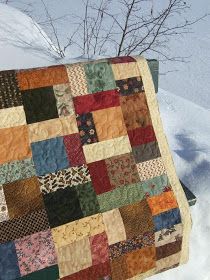 a patchwork quilt hanging from a tree in the snow