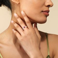 a close up of a woman with a ring on her neck and hand near her face