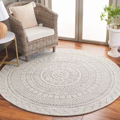 a living room with a wicker chair and large round rug on the hardwood floor