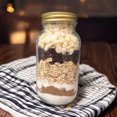 a glass jar filled with food sitting on top of a wooden table next to a black and white towel