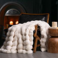 a chair with a blanket on top of it next to a fire place and candles