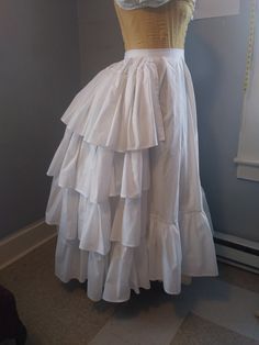 This listing is for a made to order ruffled petticoat and is made from a high quality cotton - here it is shown over a wire bustle (not included) but can be worn without one (is about 3 inches longer in the back). It closes on the left hand side with a button, One ruffle goes around the entire bottom, and additional ruffles on the back. I will need to know your waist measurement and the length of the petticoat (waist to where you want the petticoat to end). Please allow 3-4 weeks for the making of this item as it is made to order. If you have any custom requests please contact me with more details of what you're looking for - I am happy to work to your specifications!  Different fabrics & patterns available upon request (please note that a change in fabric may alter the total price of this Tiered Ruffled Petticoat, Vintage Ruffled Petticoat For Costume, Costume Ruffled Tiered Skirt, Fitted Tiered Petticoat, Fitted Full Skirt Petticoat With Gathered Skirt, Fitted Full Skirt Petticoat With Gathered Details, Fitted Full Skirt Gathered Petticoat, Cotton Ruffled Tiered Petticoat, Fitted Ruffle Cotton Skirt