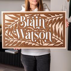 a woman holding up a wooden sign that says brain wapson in front of her face