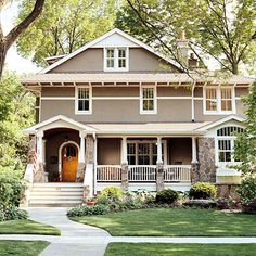 a brown house with white trim on the front porch and stairs leading up to it