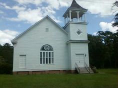 an old white church with a steeple on the front and stairs leading up to it