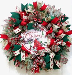 a christmas wreath with red and green bows on the front door is decorated with holly, poinsettis and ribbons