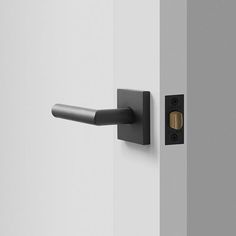 an open door with a black handle on the side and a white wall behind it