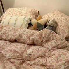 two stuffed animals are laying in the middle of an unmade bed with pink and white sheets