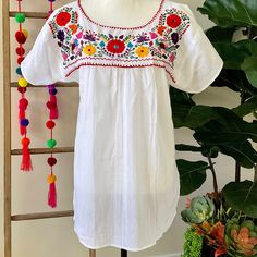 "This traditional Mexican blouse is beautifully made in Merida Yucatan, Mexico, each piece is individually hand made and hand embroidered.  You will love this lightweight blouse made of organic cotton, this natural material gives the blouse a delicate and relaxed feel.   Details: Size M-L measurements: Bust: 42\" - 29\" length(shoulder to bottom Hem) Cotton  thread Embroidered Material: 100% Cotton All items are shipped from the US All Mi Mundo Mexicano  items are 100% handmade by artisans in Mexico. Each stitch and item is completely unique and one-of-a-kind, so you'll never find two that are exactly the same! All  items may vary slightly in size, color, and design - that's what makes handmade items so special and charming!  Your Purchase supports artisans craft and families" Peasant Floral Embroidered Top For Beach, Multicolor Embroidered Peasant Top, Peasant Top With Multicolor Embroidery And Embroidered Hem, Folk Style Peasant Top With Floral Embroidery For Beach, Traditional White Embroidered Top, Peasant Festival Top With Embroidered Hem, Folk Peasant Top With Multicolor Embroidered Neckline, Traditional White Peasant Top With Intricate Embroidery, Folk Style Short Sleeve Peasant Top With Embroidered Border