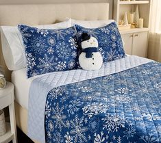 a snowman pillow sitting on top of a bed next to a night stand and nightstand