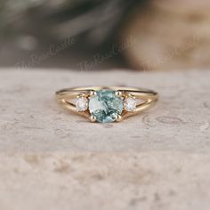 a close up of a ring with a blue stone in the middle and three diamonds on it